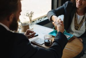 man and woman shaking hands over table with coffee