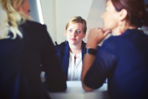 up close of woman talking across to two other women in meeting