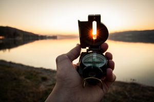 hand holding compass against the sun set